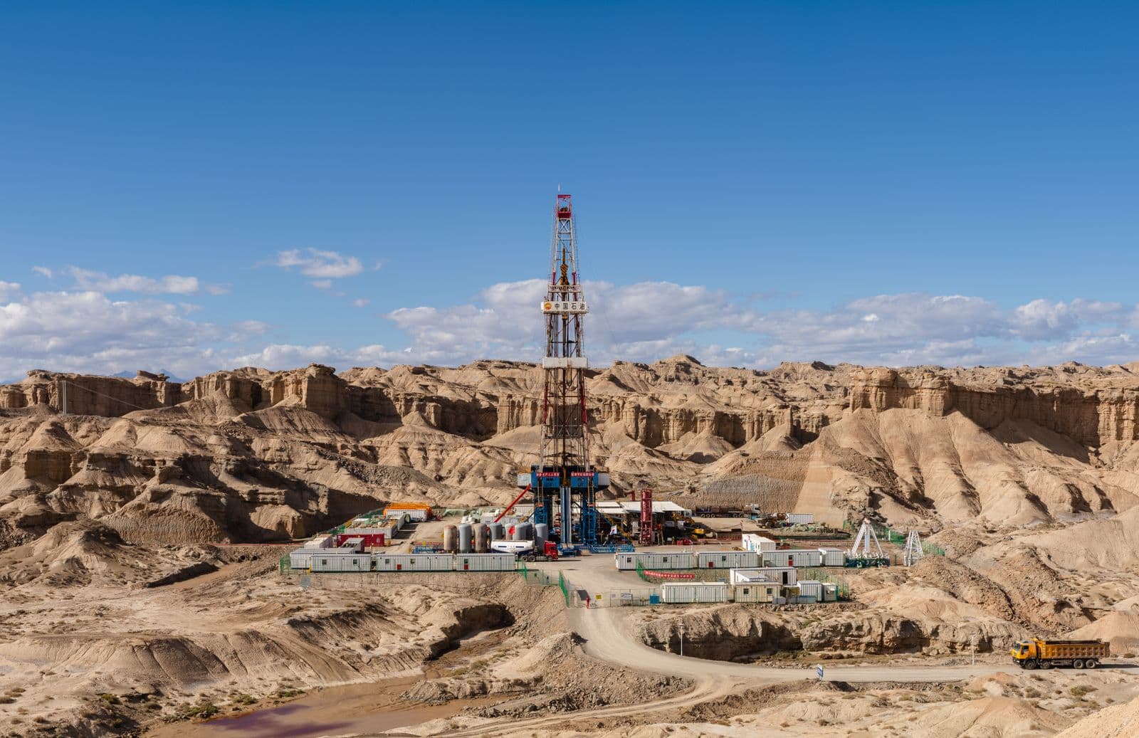 Drilling rig and lease equipment in open terrain.
